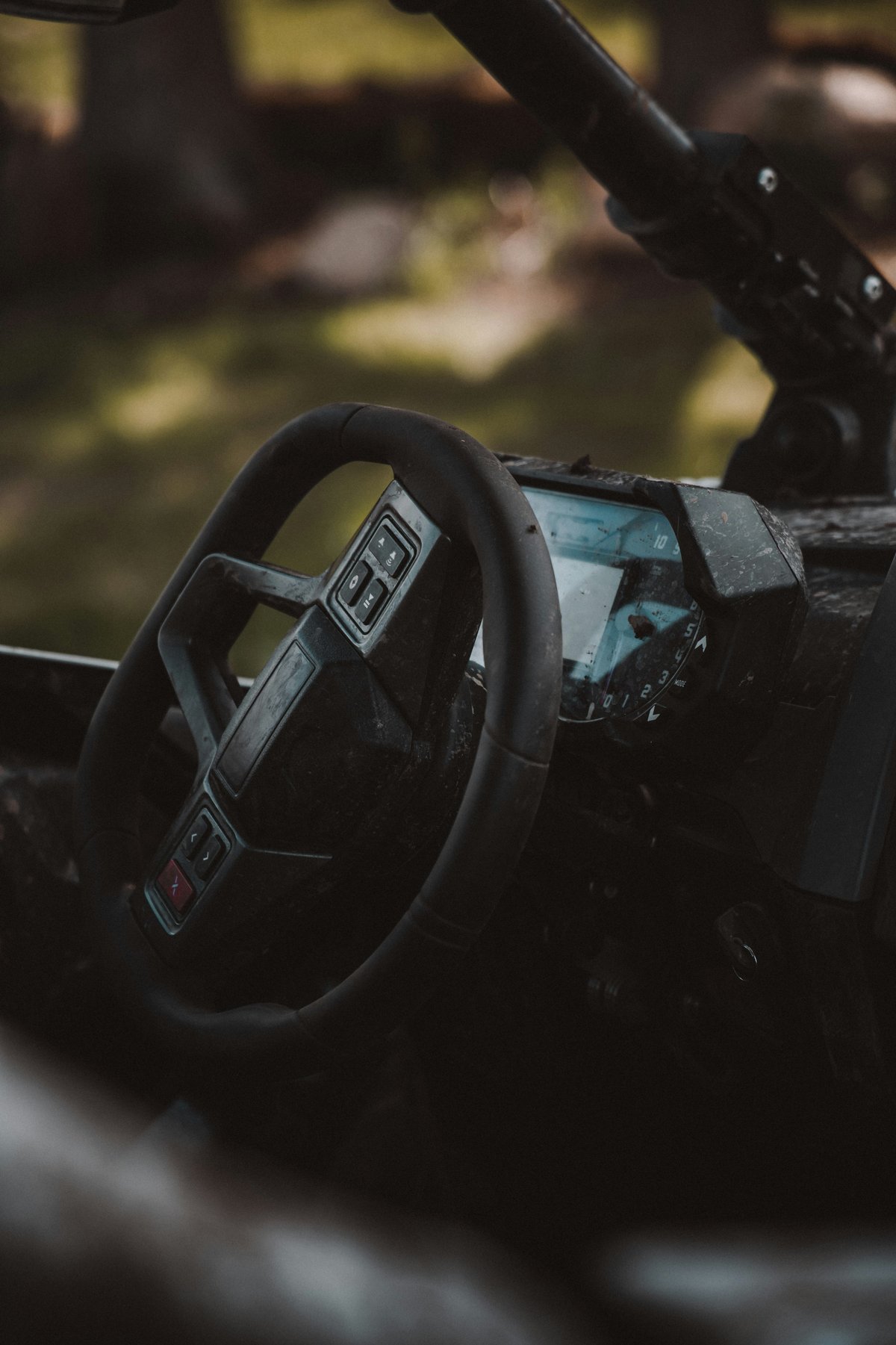 Dirty UTV cockpit with multifunction steering wheel and digital gauge cluster after an off-road ride.